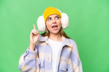 İzole edilmiş krom arka plan üzerinde kışlık manşet takan genç sarışın kadın çözümü fark etmek için parmağını kaldırıyor.