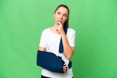 Kırık kollu genç sarışın kadın ve izole edilmiş krom anahtar arka planda askısı var. Şüpheleri var.