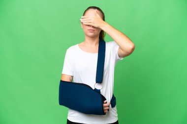 Kırık kollu genç sarışın kadın ve izole edilmiş krom anahtar arka planda elleri ve gözleri kaplayan bir askısı var. Bir şey görmek istemiyorum.