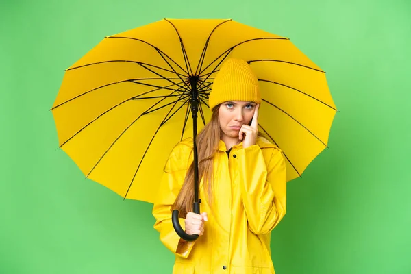 若いですブロンド女性とともにレインプルーフコートと傘上の隔離されたクロマキー背景考え方 — ストック写真