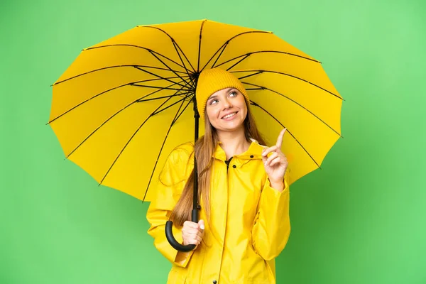 若いですブロンド女性とともにレインプルーフコートと傘上の隔離されたクロマキー背景指摘素晴らしいですアイデア — ストック写真