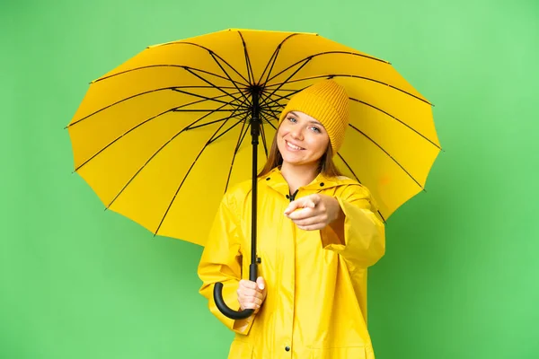 若いですブロンド女性とともにレインプルーフコートと傘上の隔離されたクロマキー背景ポインティングフロントで幸せな式 — ストック写真