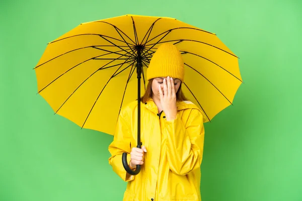 若いですブロンド女性とともにレインプルーフコートと傘上の隔離されたクロマキー背景とともに疲れと病気の式 — ストック写真
