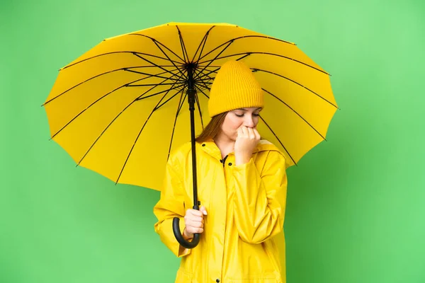 若いですブロンド女性とともにレインプルーフコートと傘上の隔離されたクロマキー背景持っています疑問 — ストック写真