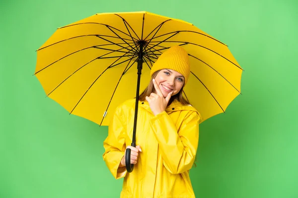 若いですブロンド女性とともにレインプルーフコートと傘上の隔離されたクロマキー背景幸せと笑顔 — ストック写真