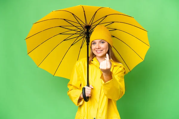 若いですブロンド女性とともにレインプルーフコートと傘上の隔離されたクロマキーバックやりますジェスチャー — ストック写真