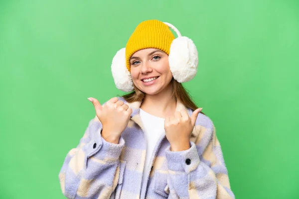年轻的金发女郎 戴着冬季的围巾 戴在孤立的彩色关键背景上 竖起大拇指 微笑着 — 图库照片