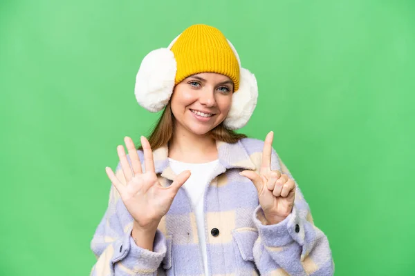 年轻的金发女郎穿着冬季的围巾 戴在孤立的彩色关键背景上 手指数着7个 — 图库照片