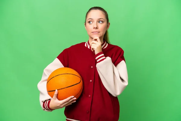若いですブロンド女性プレイバスケットボール上の隔離されたクロマキー背景持っています疑問と思考 — ストック写真