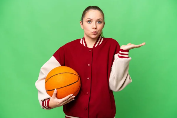 若いですブロンド女性プレイバスケットボール上の隔離されたクロマキー背景持っています疑問ながら手を上げます — ストック写真