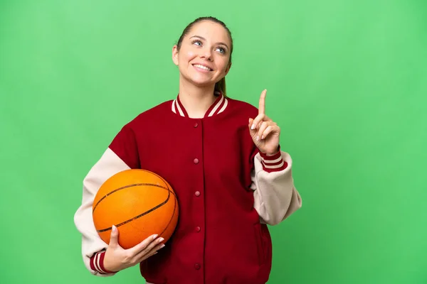 Młoda Blondynka Gra Koszykówkę Odizolowanym Tle Chroma Key Wskazując Świetny — Zdjęcie stockowe