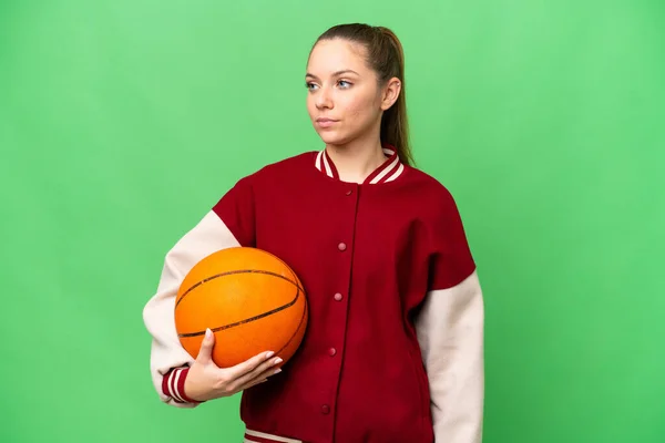 若いですブロンド女性プレイバスケットボール上の隔離されたクロマキー背景見ますザ側 — ストック写真