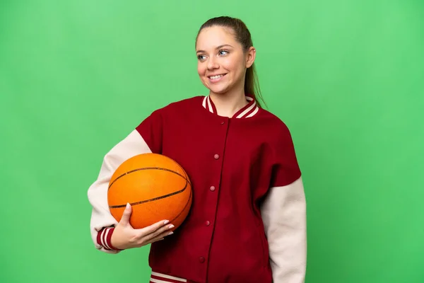 若いですブロンド女性プレイバスケットボール上の隔離されたクロマキー背景見ますへザ側と笑顔 — ストック写真