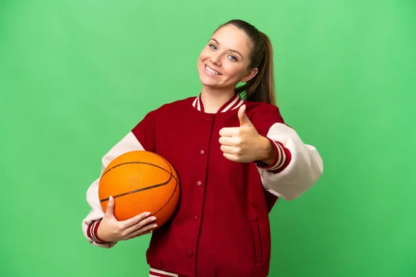 年轻的金发女子在孤零零的彩色关键背景上打篮球 大拇指竖起 因为发生了件好事 — 图库照片