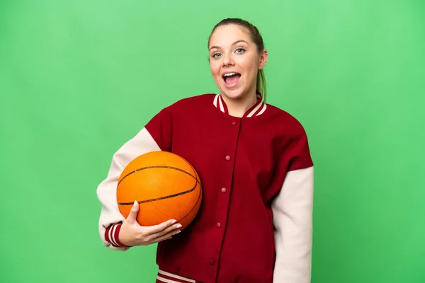 年轻的金发女子在孤零零的彩色关键背景上打篮球 脸上带着惊讶的表情 — 图库照片