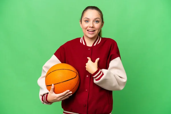 年轻的金发女子在孤零零的彩色关键背景上打篮球 脸上带着惊讶的表情 — 图库照片