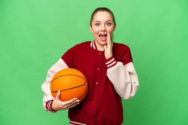若いですブロンド女性遊びバスケットボール上の隔離されたクロマキー背景とともに驚きとショックを受けた顔の表情 — ストック写真
