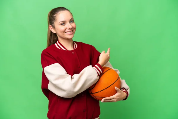 若いですブロンド女性プレイバスケットボール上の隔離されたクロマキー背景ポインティングバック — ストック写真