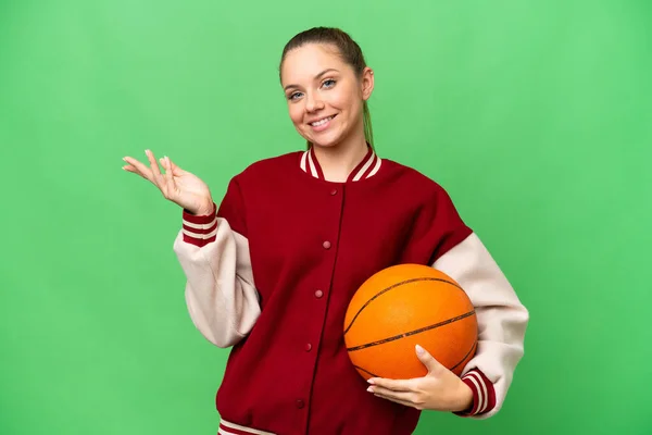 年轻的金发女子在孤零零的有色人种背景下打篮球 她向旁边伸出手来 感谢对方邀请她来 — 图库照片