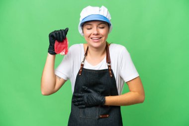 Kasap kadın önlük takıyor ve izole edilmiş krom anahtar arka planda taze et servis ediyor.