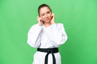 Karate yapan genç sarışın kadın izole edilmiş krom anahtar arka planda hayal kırıklığına uğramış ve kulaklarını kapatmış.