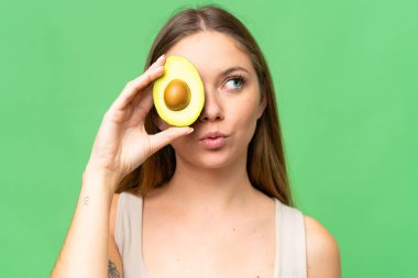 Avokado tutan, izole edilmiş krom anahtar geçmişi olan genç sarışın bir kadın. Portreyi kapat