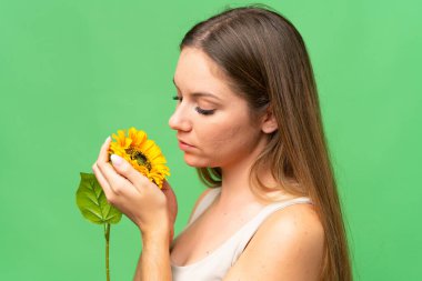 Ayçiçeği tutan, izole edilmiş krom anahtar arka planı olan genç sarışın kadın. Portreyi kapat