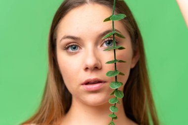 Sarışın bir kadın okaliptüs dalıyla izole edilmiş krom anahtar arka planda. Portreyi kapat