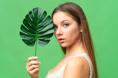 Elinde palmiye yaprağı tutan izole edilmiş krom anahtarlı genç sarışın kadın. Portreyi kapat