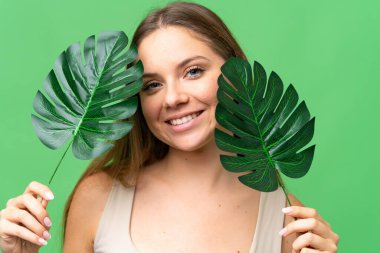 Sarışın, izole edilmiş, anahtar arka planda, elinde mutlu bir ifadeyle palmiye yaprağı tutan genç bir kadın. Portreyi kapat