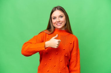 Sarışın, izole edilmiş, anahtar geçmişi olan genç bir kadın baş parmak işareti yapıyor.