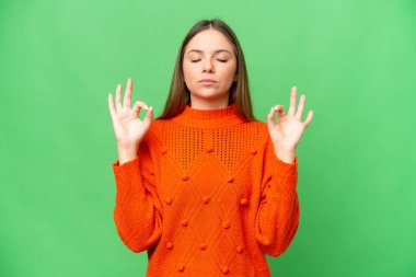 Zen pozunda izole edilmiş krom anahtar arka planı olan genç sarışın kadın.