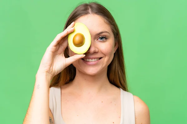Young Blonde Woman Isolated Chroma Key Background Holding Avocado While — Stock Photo, Image