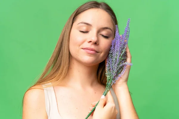 Young blonde woman over isolated chroma key background holding a lavender plant. Close up portrait