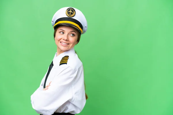 Airplane pilot woman over isolated chroma key background with arms crossed and happy