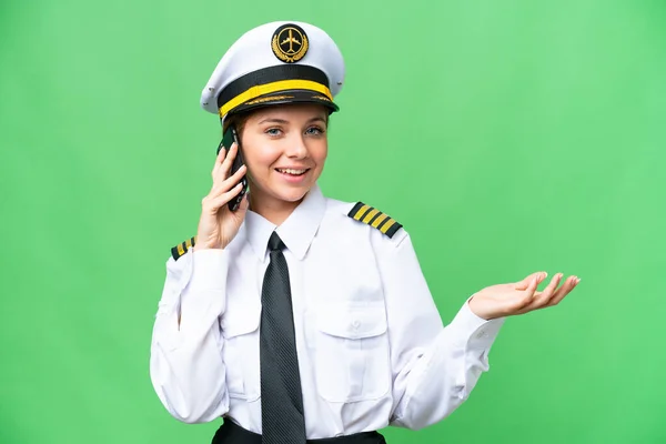 stock image Airplane pilot woman over isolated chroma key background keeping a conversation with the mobile phone with someone