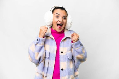 İzole edilmiş beyaz arka planda kış maskesi takan genç bir kadın galibiyeti kutluyor.