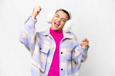 İzole edilmiş beyaz arka planda kış pantolonu giyen genç bir kadın zaferi kutluyor.