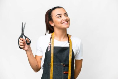 Seamstress woman over isolated white background thinking an idea while looking up