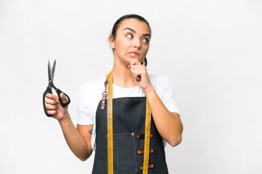Seamstress woman over isolated white background having doubts and thinking