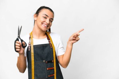 Seamstress woman over isolated white background pointing finger to the side