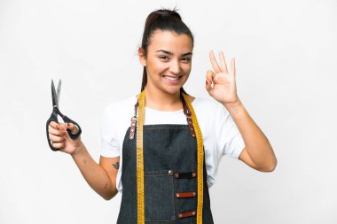 Seamstress woman over isolated white background showing ok sign with fingers