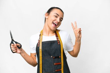 Seamstress woman over isolated white background smiling and showing victory sign