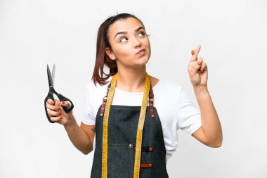 Seamstress woman over isolated white background with fingers crossing and wishing the best