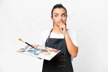 Soyutlanmış beyaz arka plan üzerinde palet tutan genç bir sanatçı. Şüpheleri ve düşünceleri var.