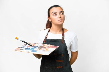 İzole edilmiş beyaz arka plan üzerinde palet tutan genç bir sanatçı.