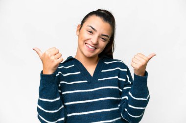 Soyutlanmış beyaz bir geçmişi olan genç ve güzel bir kadın. Baş parmakları havada ve gülümsüyor.