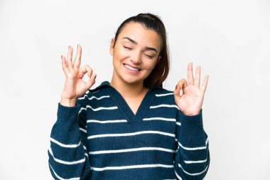 Zen pozunda soyutlanmış beyaz bir arka plan üzerinde genç bir kadın.