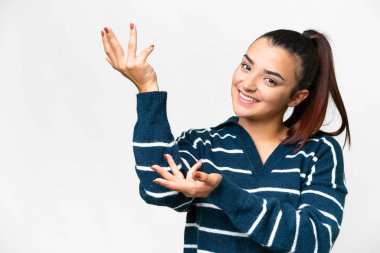 İzole edilmiş beyaz arka planda genç bir kadın. Davet edilmek için ellerini yana uzatıyor.