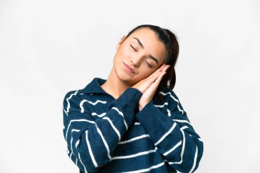 İzole edilmiş beyaz arka planda genç bir kadın uyku jesti yapıyor.